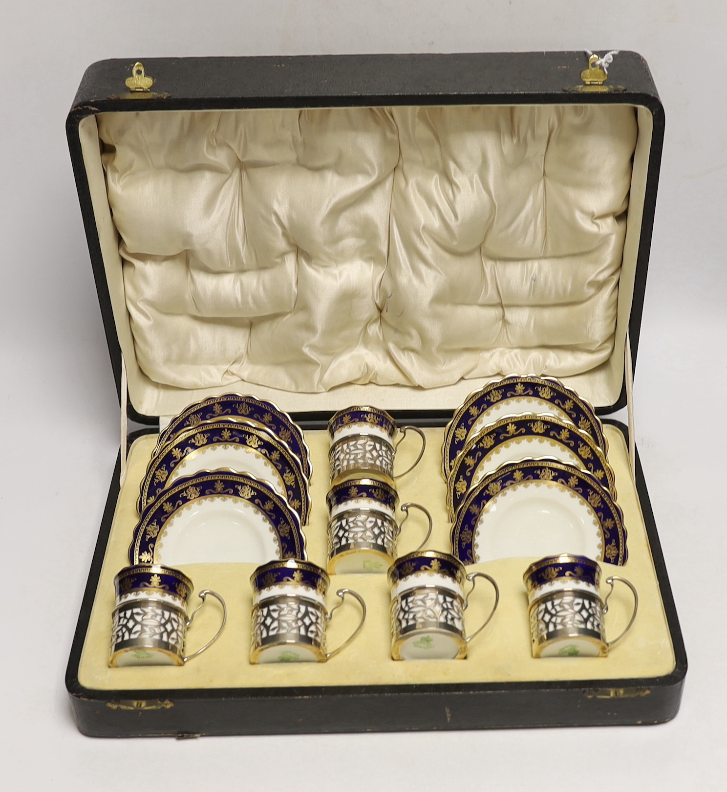 A cased George V set of six Aynsley coffee cans and saucers, the cans with pierced silver holders, C.S. Green & Co, Birmingham, 1924, can 57mm.